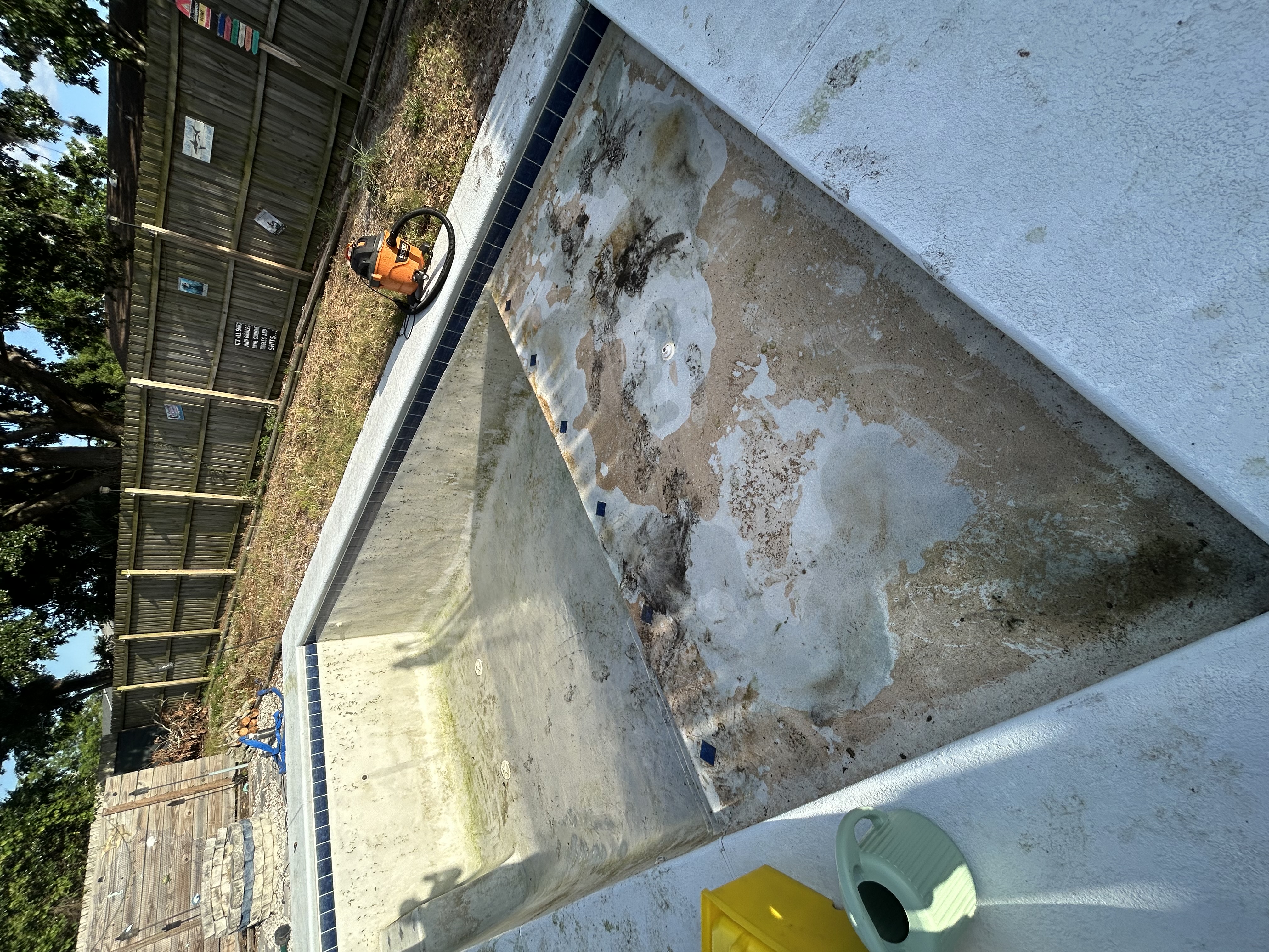 Drained pool with heavy mineral staining and peeling plaster — before acid wash service in Orlando FL